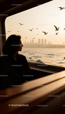 Woman gazing at seagulls and city skyline at sunset
