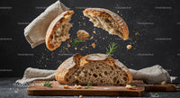 Rustic Bread Breaking with Flying Crumbs and Herbs