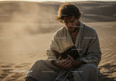 Man Reading Book in Desert Sand with Sunset Light