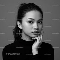 Elegant Black and White Portrait of Woman with Hoop Earrings and Thoughtful Expression