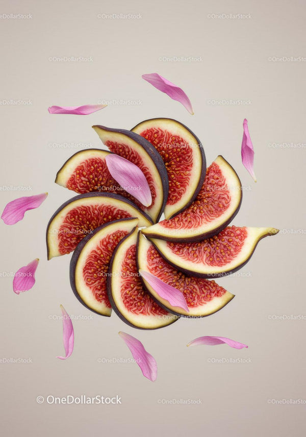 Fresh ripe fig slices with pink flower petals on beige