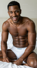 Smiling muscular man in white underwear on bed