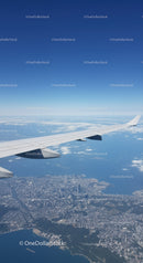 Aerial View of Cityscape with Airplane Wing in Clear Blue Sky