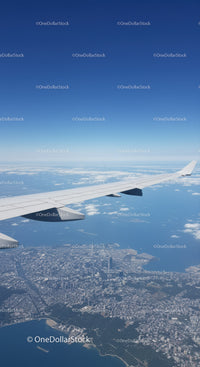 Aerial View of Cityscape with Airplane Wing in Clear Blue Sky