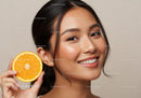 Beautiful Woman Smiling with Fresh Orange Slice on Her Face