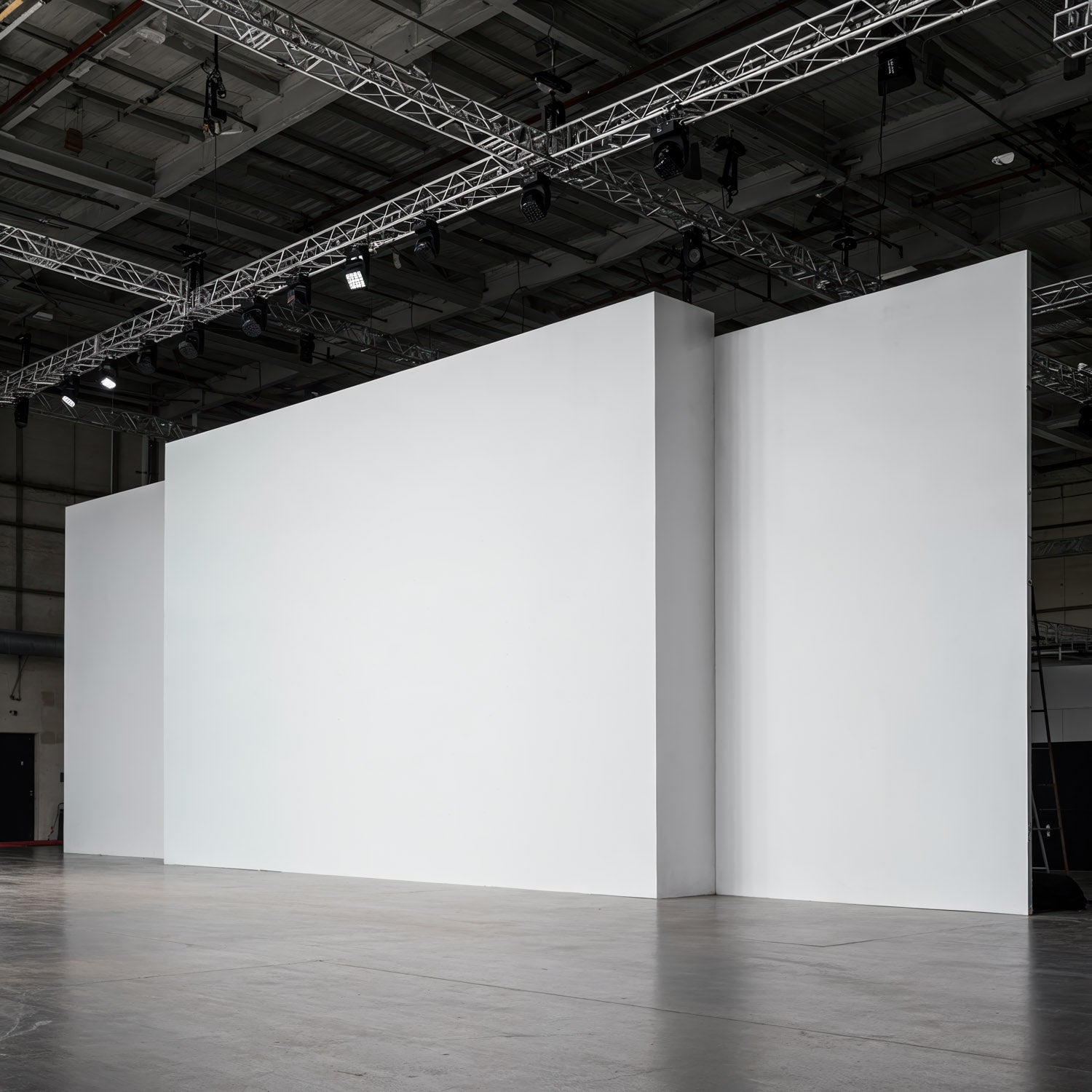Empty white exhibition walls with industrial ceiling lights