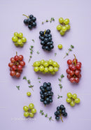 Assorted fresh grapes with herbs on pastel background