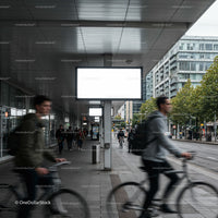 Urban commuters cycling past illuminated blank billboards