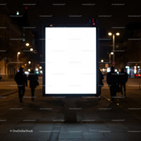 Illuminated blank billboard on urban street at night