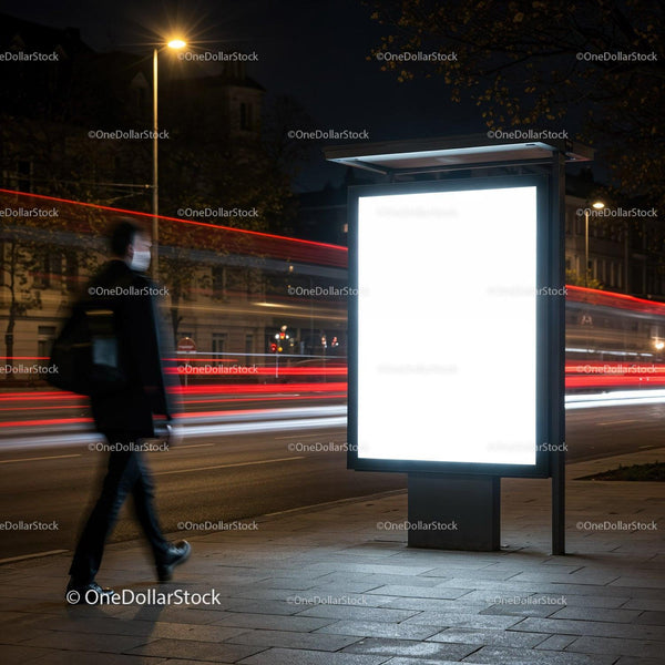 Man Walking Past Illuminated Bus Stop Advertisement at Night JPG Mockup Image