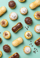 Variety of Mini Eclairs and Cream Tarts on Blue Background
