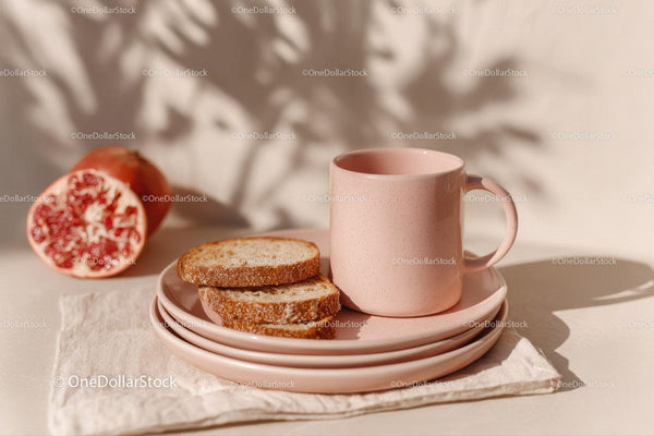 Różowy ceramiczny kubek i opieczony chleb z granatem na eleganckiej zastawie stołowej
