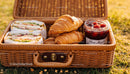 Delicious picnic basket with sandwiches croissants and jam