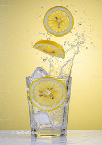 Fresh lemon slices splashing into clear water glass