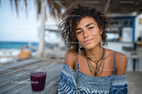 Young Woman Smiling at Tropical Beachside with Refreshing Drink