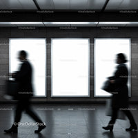 Blurred commuters walking past illuminated ad panels