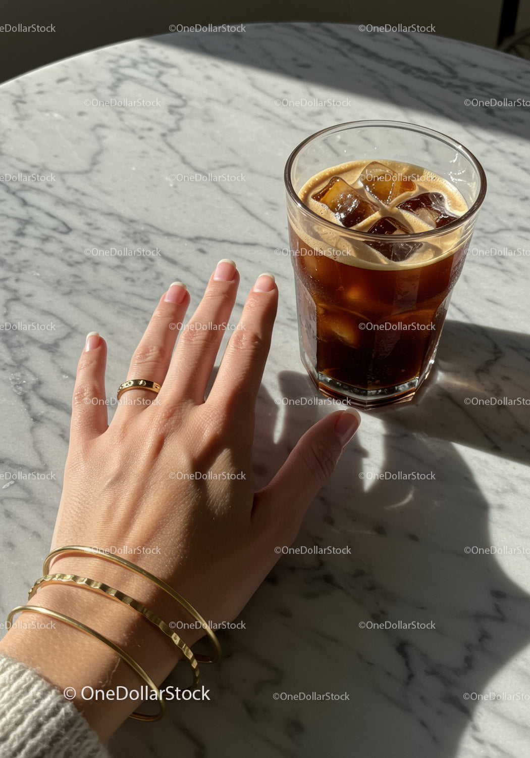 Hand with Gold Bracelets Next to Glass of Iced Coffee