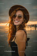 Young Woman in Straw Hat and Sunglasses Smiling at Sunset on Beach
