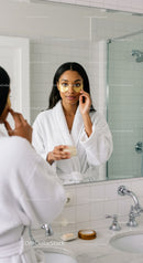Young Woman Applying Eye Patches During Skincare Routine in Bathroom