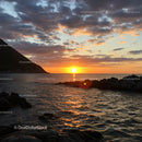 Beautiful Sunset Over Calm Ocean with Rocky Shore and Dramatic Sky
