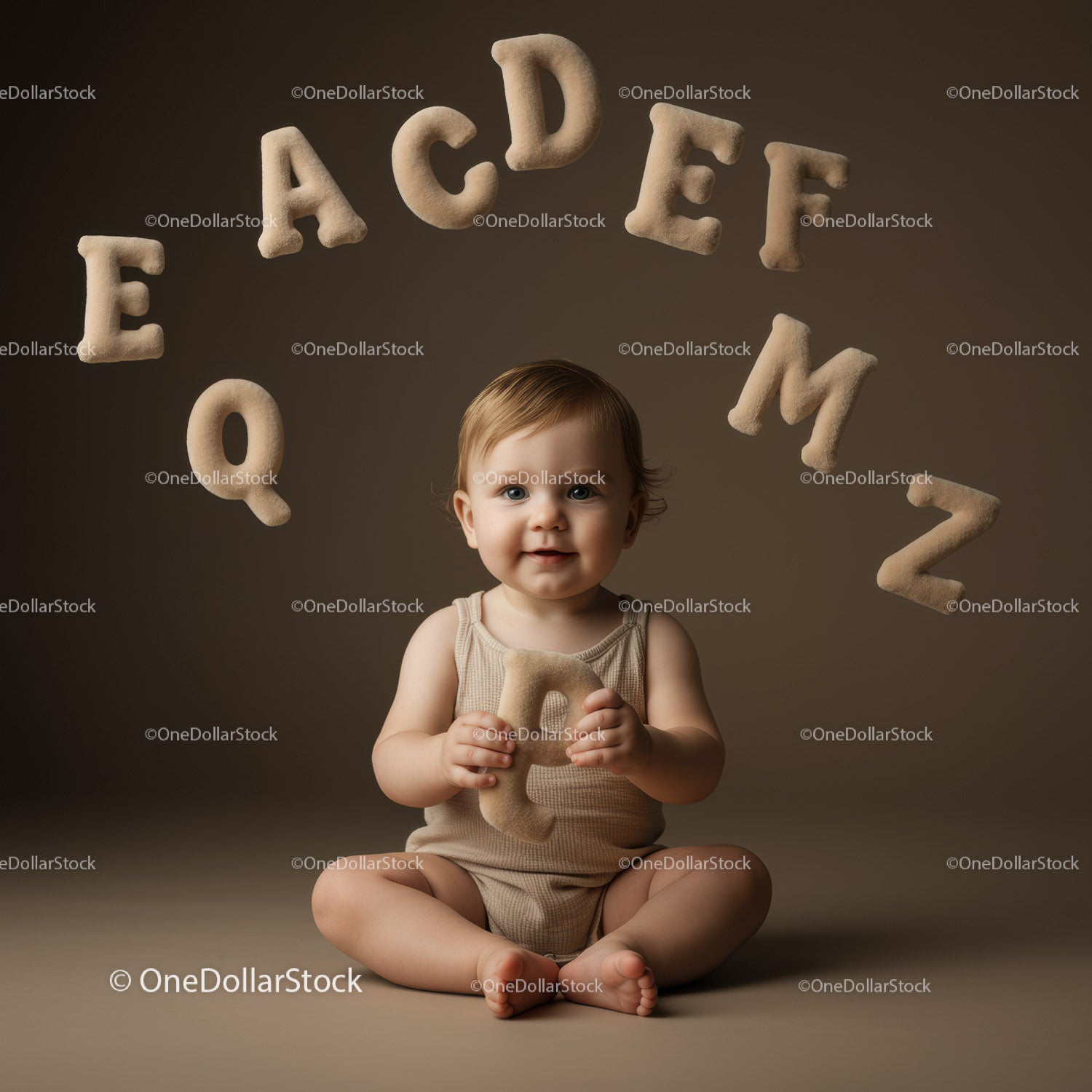 Adorable baby holding fuzzy letter with alphabet arc