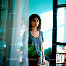Young woman standing by window in sunlit room