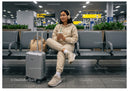 Young Woman with Suitcase and Coffee Waiting in Airport Lounge