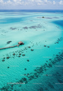 Overwater Bungalow with Pier over Turquoise Coral Reefs in Clear Blue Sea
