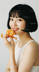 Young Woman with Short Black Hair Smiling and Holding Orange