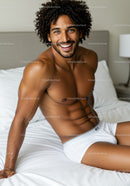 Smiling muscular man relaxing on white bed at home