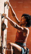 Focused woman climbing indoor rock wall with determination