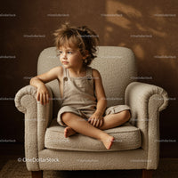 Thoughtful child sitting crosslegged on beige armchair