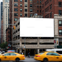 Busy urban intersection with blank billboard and yellow cabs