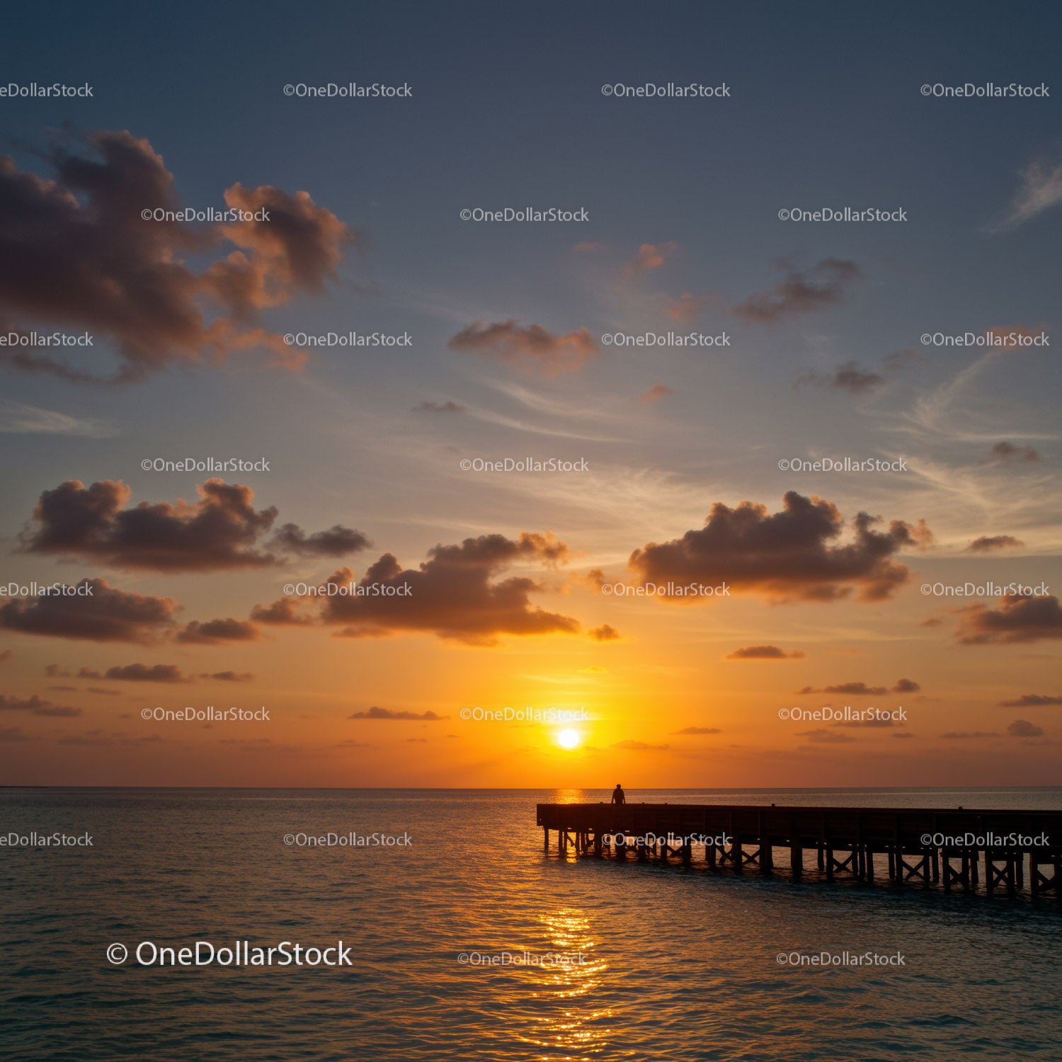 Beautiful Sunset Over Calm Ocean With Pier and Cloudy Sky