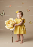 Toddler girl in yellow dress holding giant flower stem