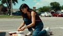 Young woman kneeling on street enjoying casual snack