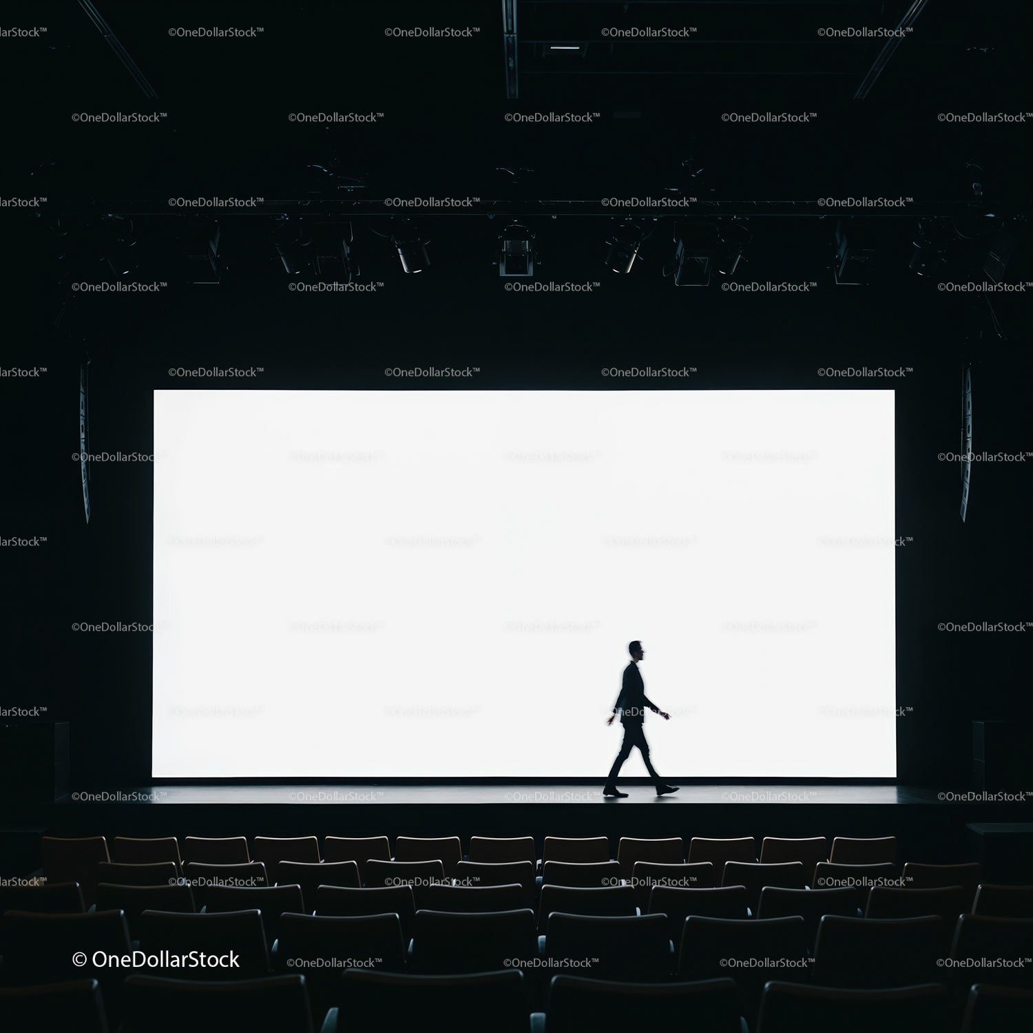 Silhouette of man walking across empty theater stage
