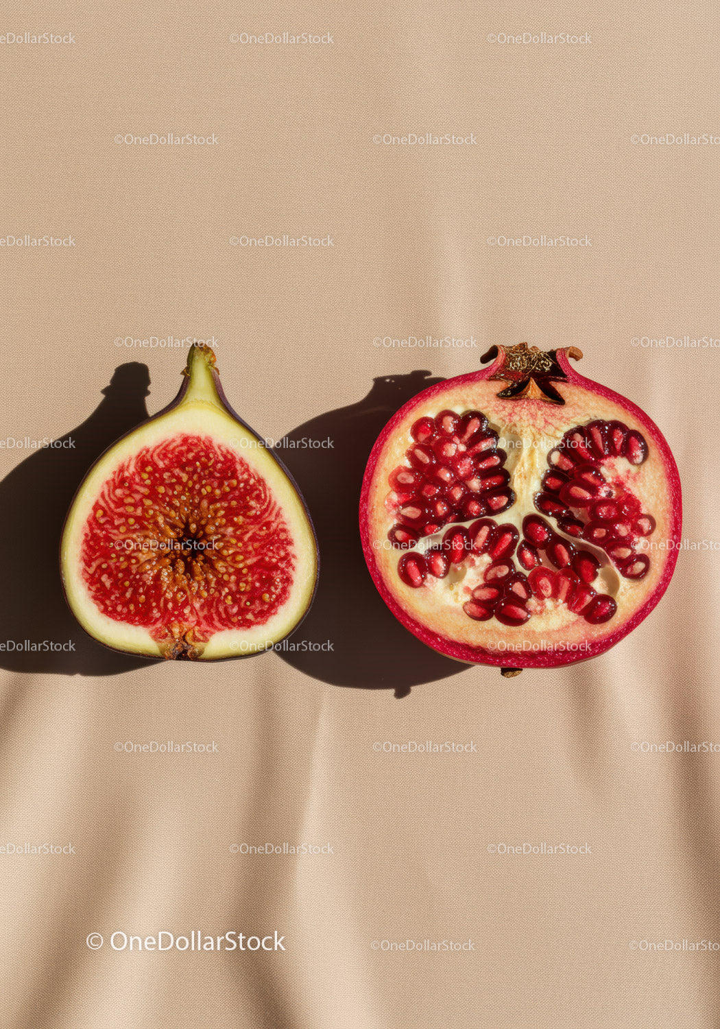 Halved ripe fig and pomegranate on beige surface