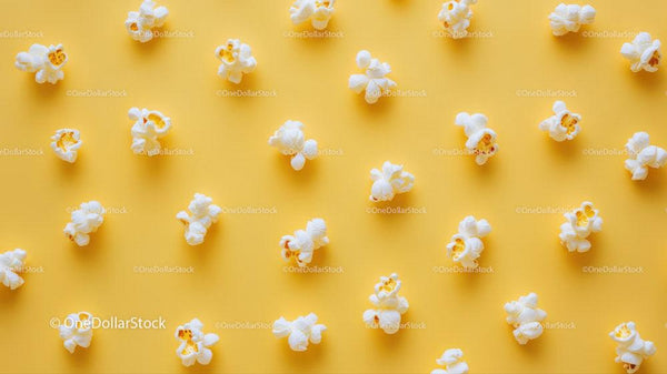 Popcorn scattered on yellow background ideal for snack or cinema themes