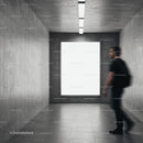 Man Passing by Blank Poster in Modern Concrete Hallway