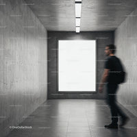 Man Passing by Blank Poster in Modern Concrete Hallway