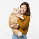Smiling woman holding fluffy cream cat indoors