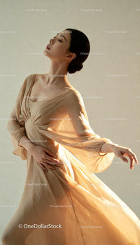 Graceful woman in flowing beige dress with soft light