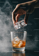 Hand Adding Ice Cubes to Whiskey Glass with Mist