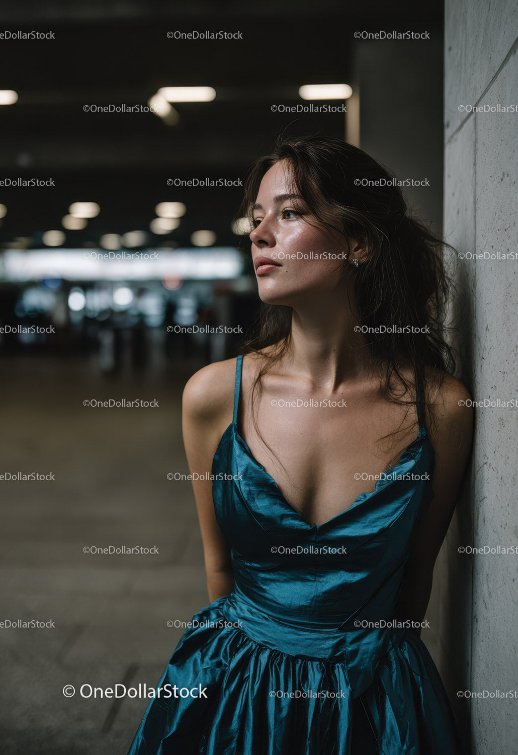 Stylish Woman in Blue Satin Dress Leaning Against Wall in Urban Setting