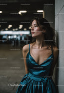 Stylish Woman in Blue Satin Dress Leaning Against Wall in Urban Setting