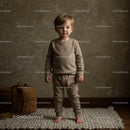 Toddler boy standing barefoot on textured rug indoors