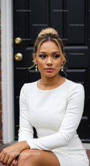 Elegant woman in white dress sitting by black door