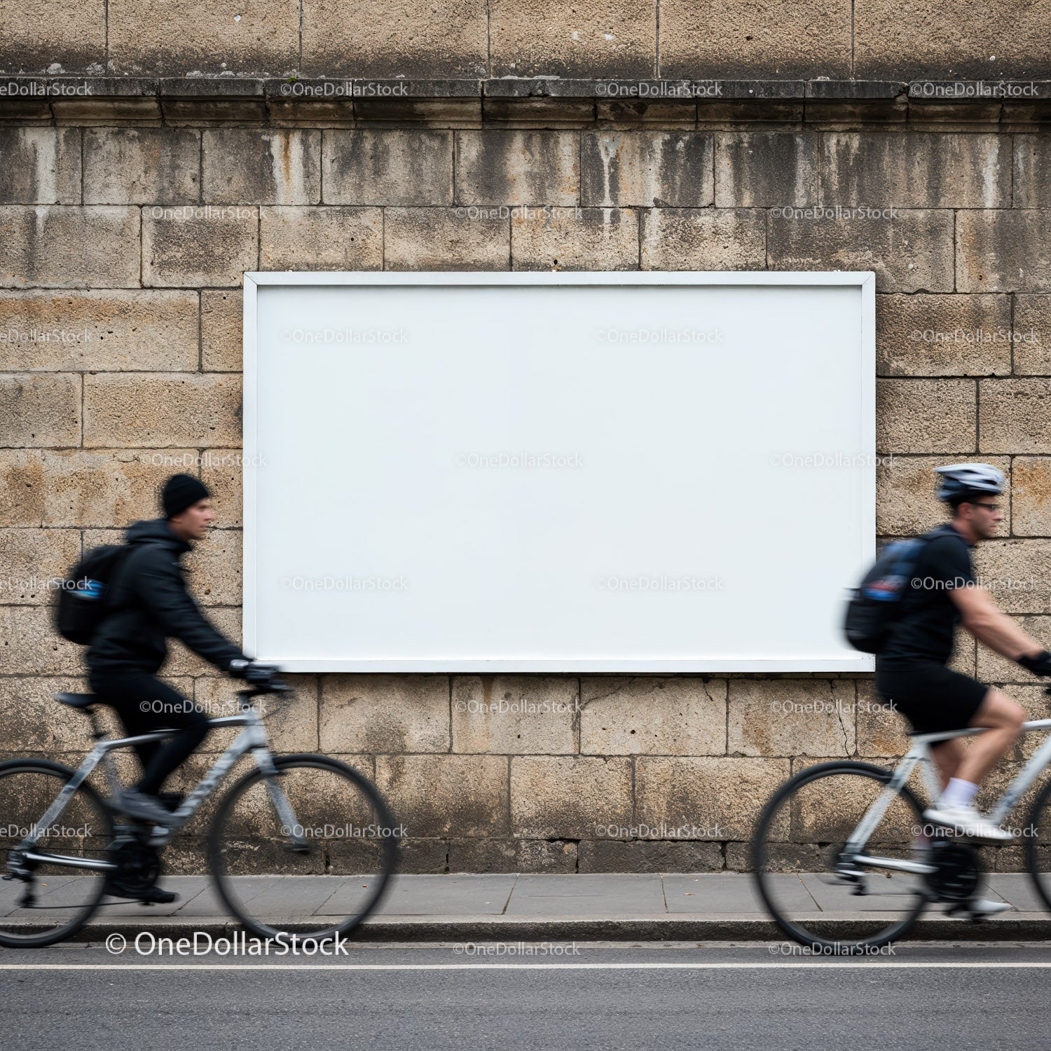 Rowerzyści przejeżdżający obok pustego billboardu na kamiennym murze