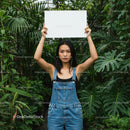 Confident Woman in Denim Overalls Surrounded by Tropical Plants